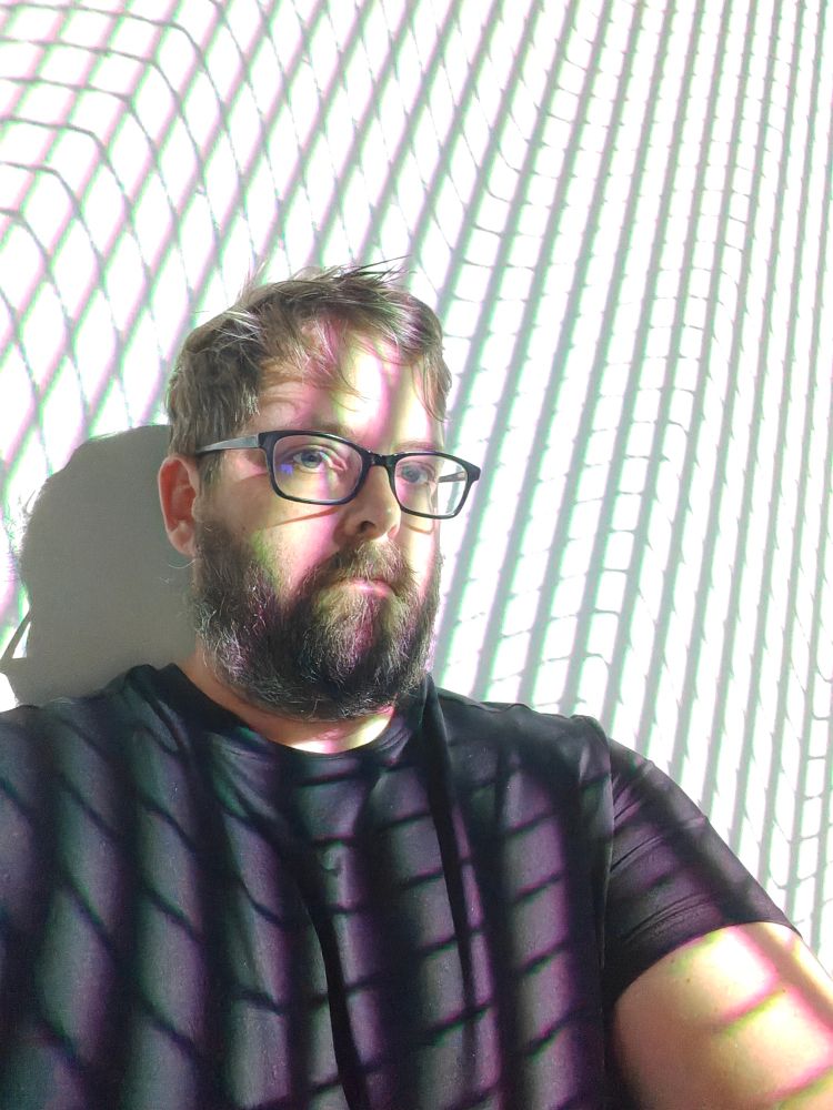 A selfie of me in front of a white wall with black lines 