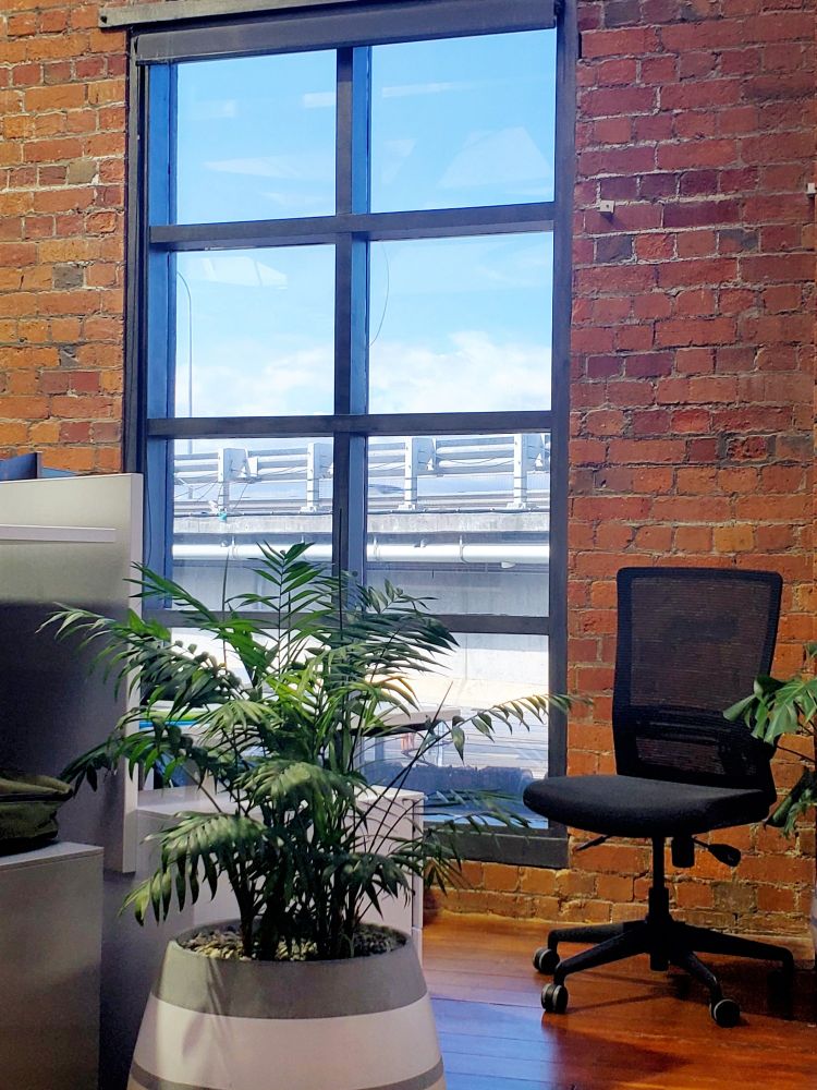 A view across an office out a large window. The only thing visible out the window is a busy motorway flyover.