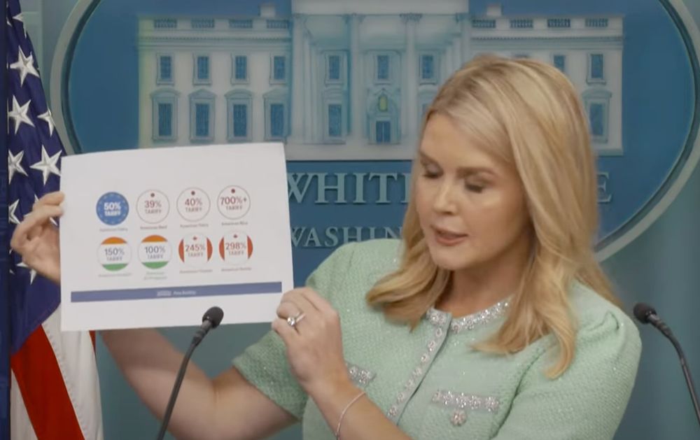 Propaganda Barbie holding up some bullshit paper with colors and numbers. At least they got the colors of the flags for each country right.