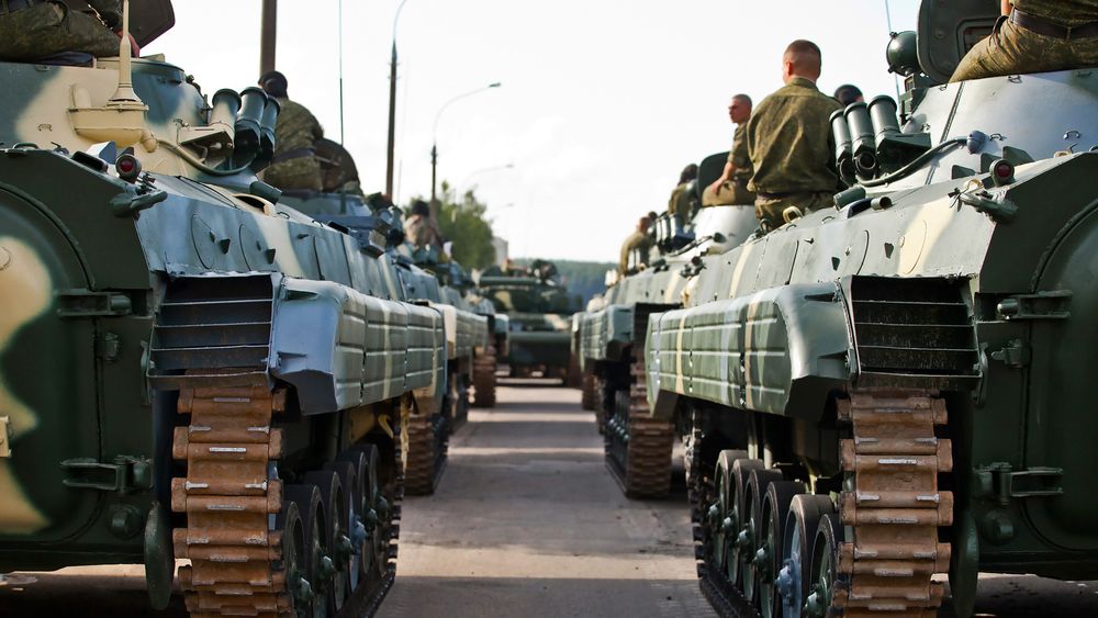 Photo: View along a road. Armoured columns with crews on the left and right.