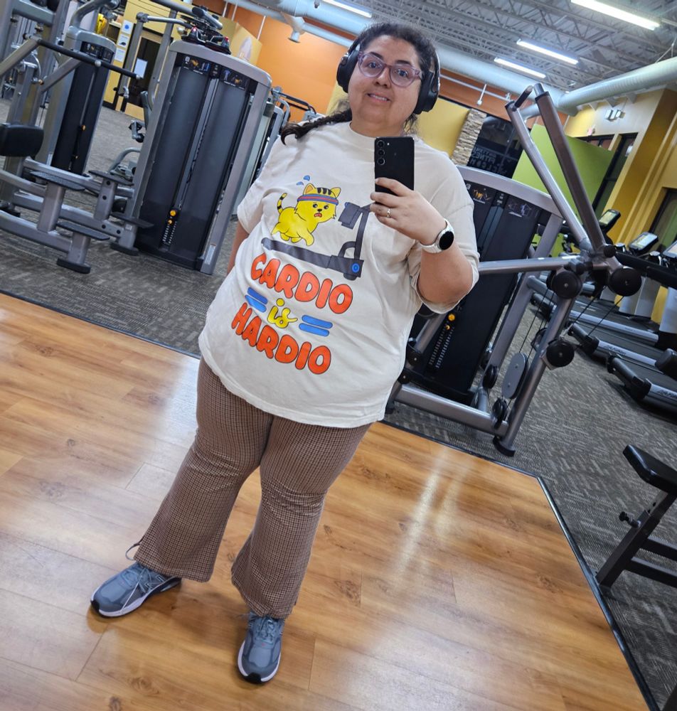 Jenna wearing a shirt with a cat running on a treadmill that reads "Cardio is Hardio"