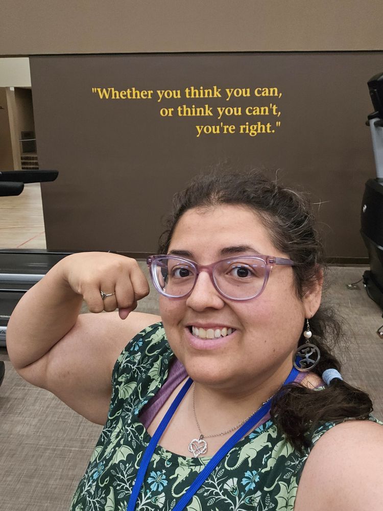 Jenna flexing her arm in front of a quotation that reads "Whether you think you can, or you think you can't, you're right."