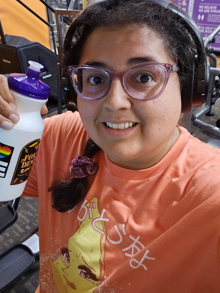 Jenna holding a water bottle while standing on an elliptical machine 