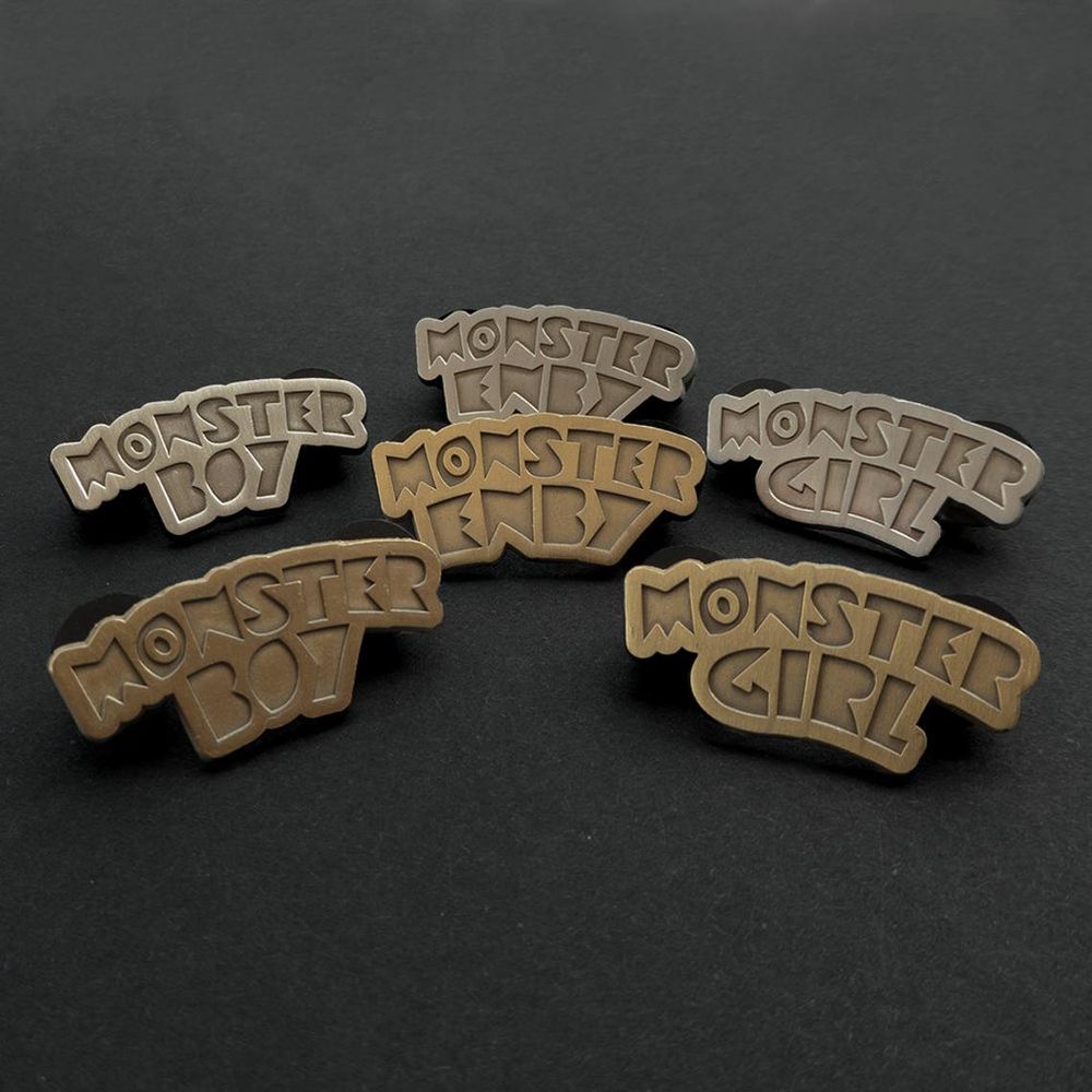 collection of monster boy, monster girl, and monster enby metallic pins.