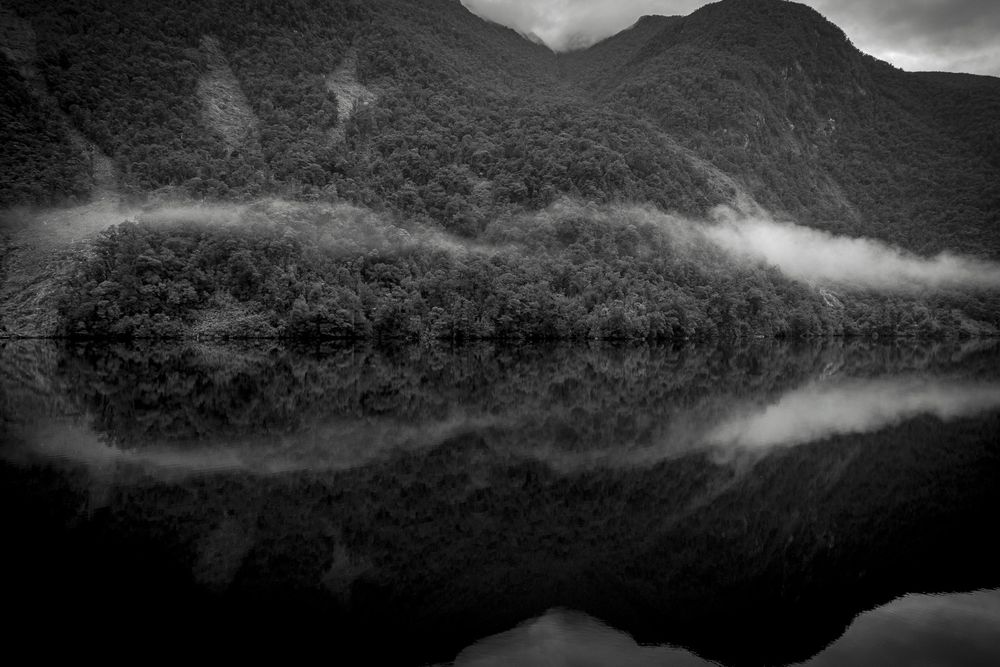 Photo of Doubtful Sound in Aeoteroa New Zealand with clouds/mist reflecting in the still water