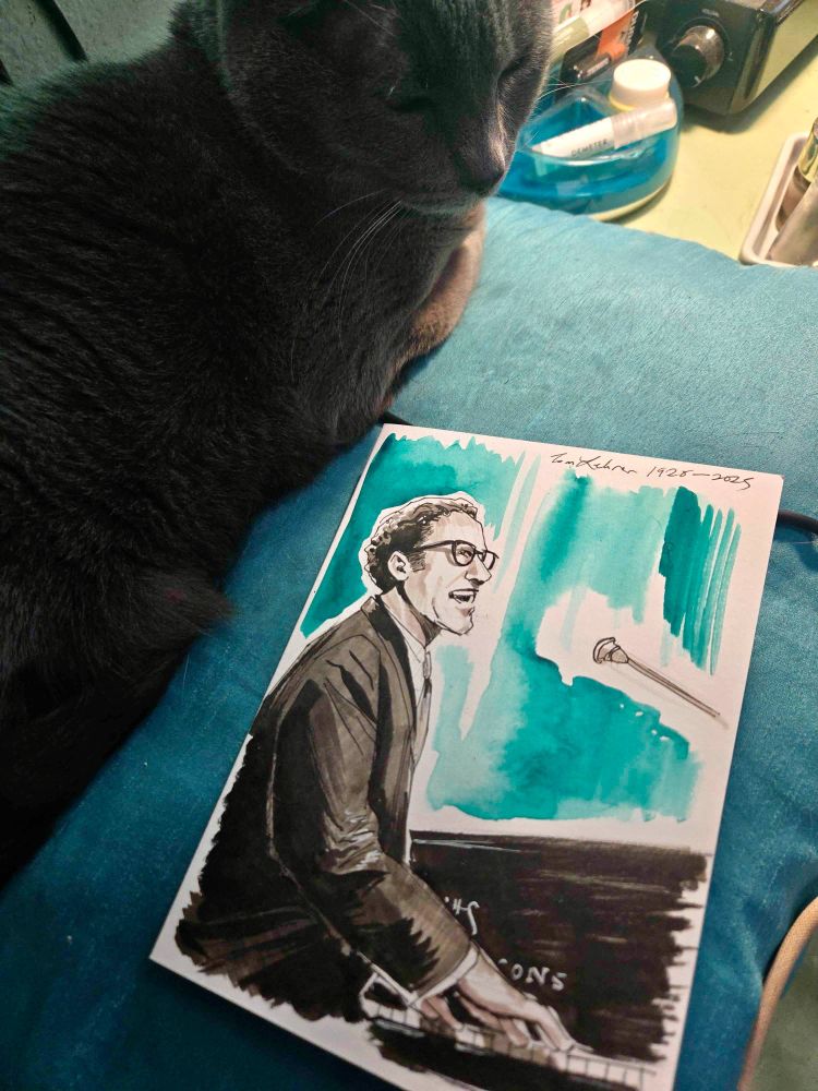 A gray cat sitting next to a drawing of tom lehrer