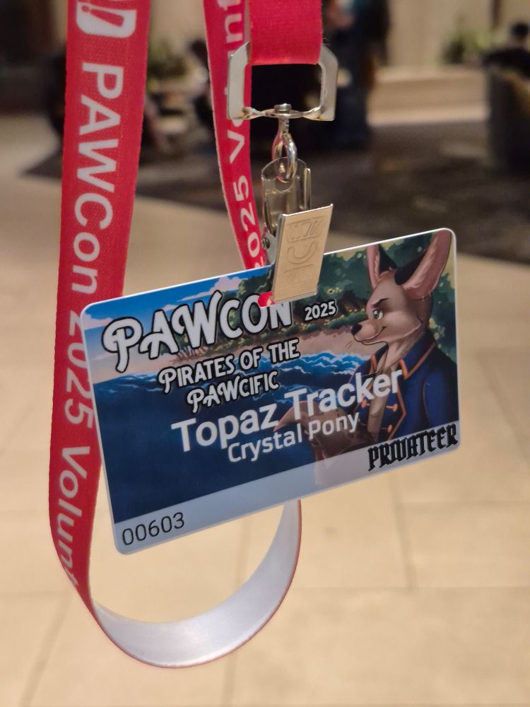 Photo of the user's attending badge for PAWCon 2025 on a red lanyard with the text, "PAWCon 2025 Volunteer".

The badge card reads, "PAWCon 2025 Pirates of the Pawcific", with the name "Topaz Tracker", the species written as "Crystal Pony", and "Privateer" for the tier level.