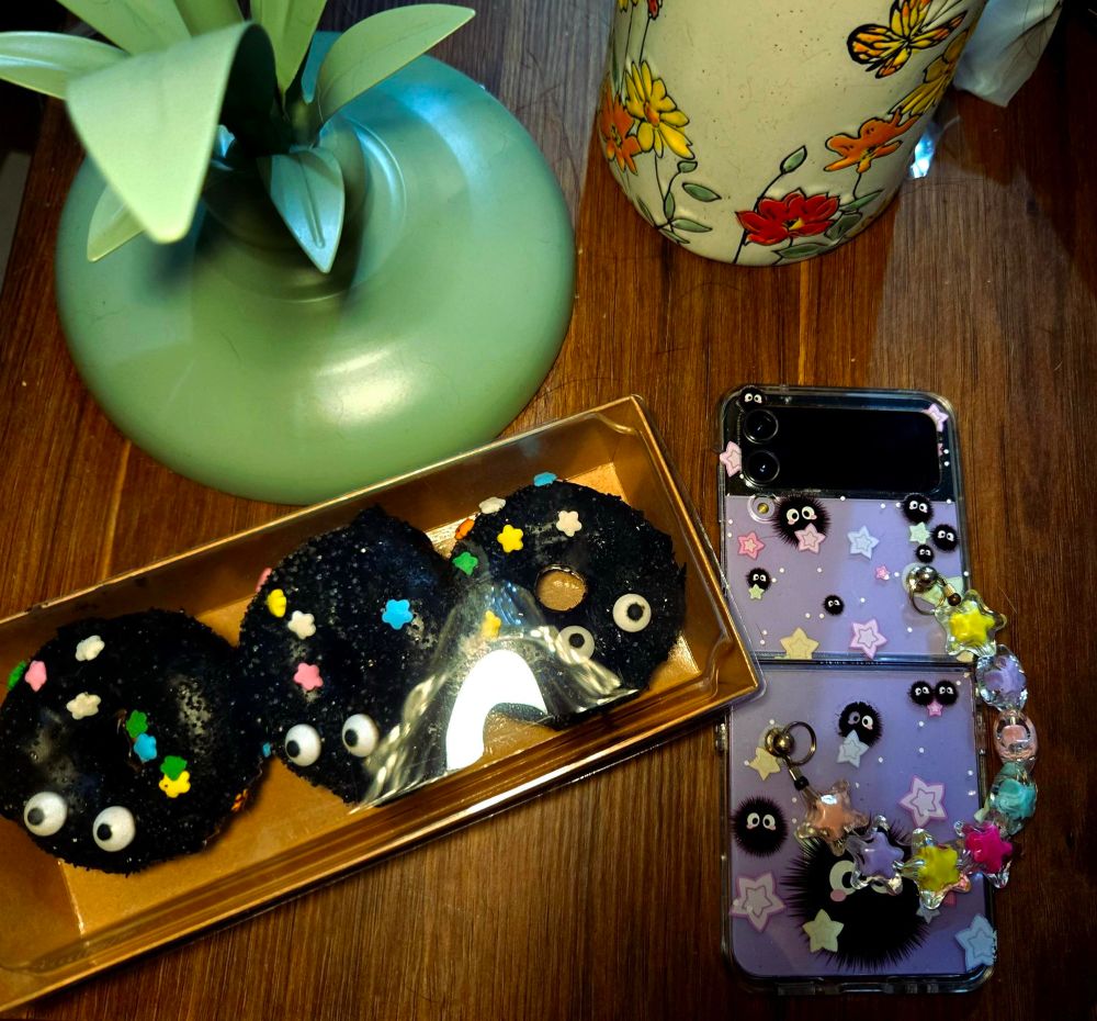 Picture of donuts that look like soot sprites from spirited away next to a phone case with soot sprites printed on it