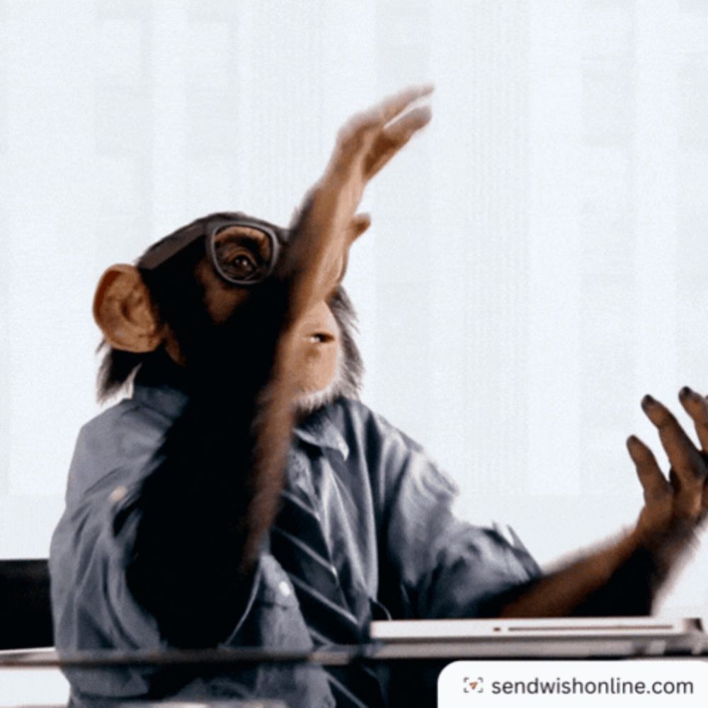 a chimpanzee wearing glasses is sitting at a desk with a sendwishonline.com logo in the corner