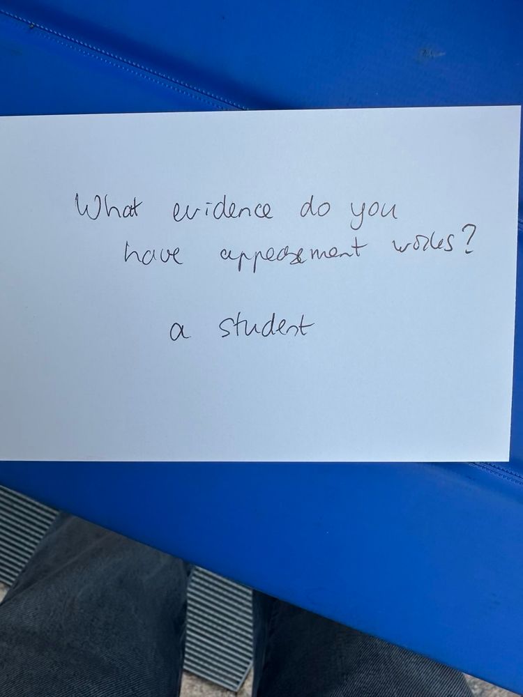 a postcard asks:

“What evidence do you have that appeasement works?” Signed: “a student”