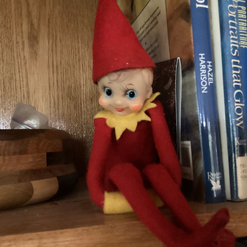 Vintage elf sitting on a book shelf.