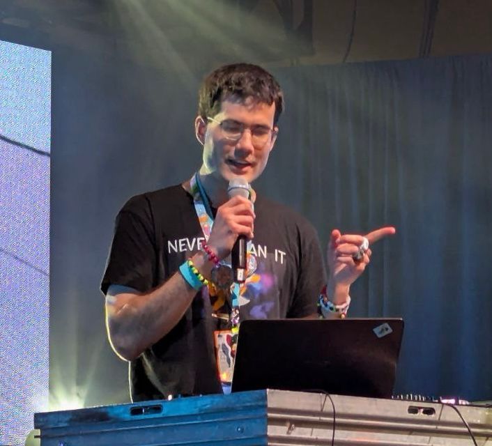 Foozogz singing Stagefright and pointing to the audience while looking at the laptop screen.