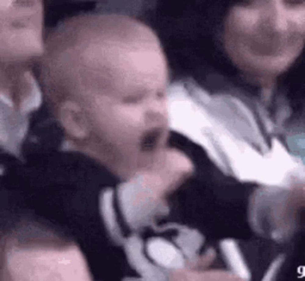 a baby is crying while sitting in a crowd of people watching a game .