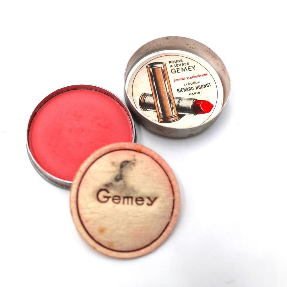 Image 4: One of several luxury French cosmetics gifted by Private Aubrey Price to his  mother, Mercy for Christmas 1944. Vibrant red Gemey powder, within a circular metal case, with circular cotton applicator and a metal top, with a loose circular paper advertising note(?) 'ROUGE / A LÉVRES / GEMEY /procédé synthochrome / création / RICHARD HUDNUT / PARIS'. Aubrey was killed two months later on the 7th March 1945 in the Netherlands and the luxury cosmetics were preserved by Mercy through her grief. For more, see https://www.soldiersofshropshire.co.uk/survived-by-grief-cosmetic-dis-comfort-a-gift-from-a-soldier-son-to-mother/