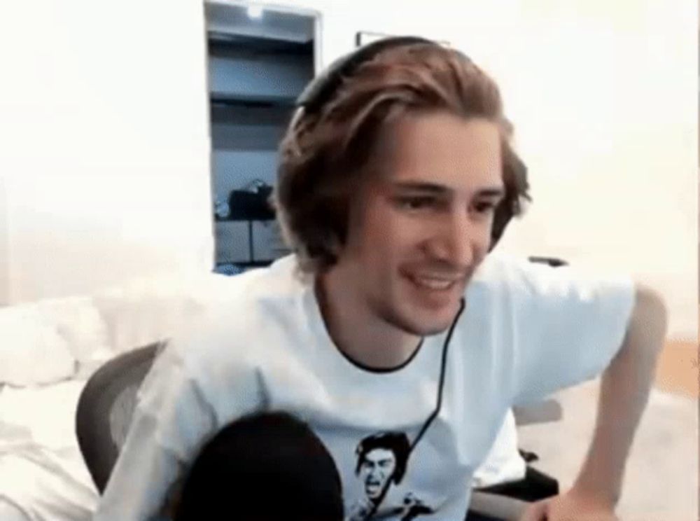 a man wearing headphones and a white shirt is smiling while sitting in front of a computer .