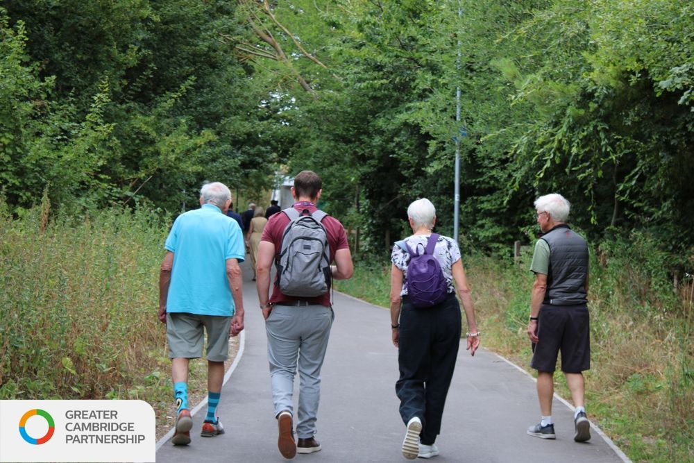 four people walking on the Meldreth Station link. 