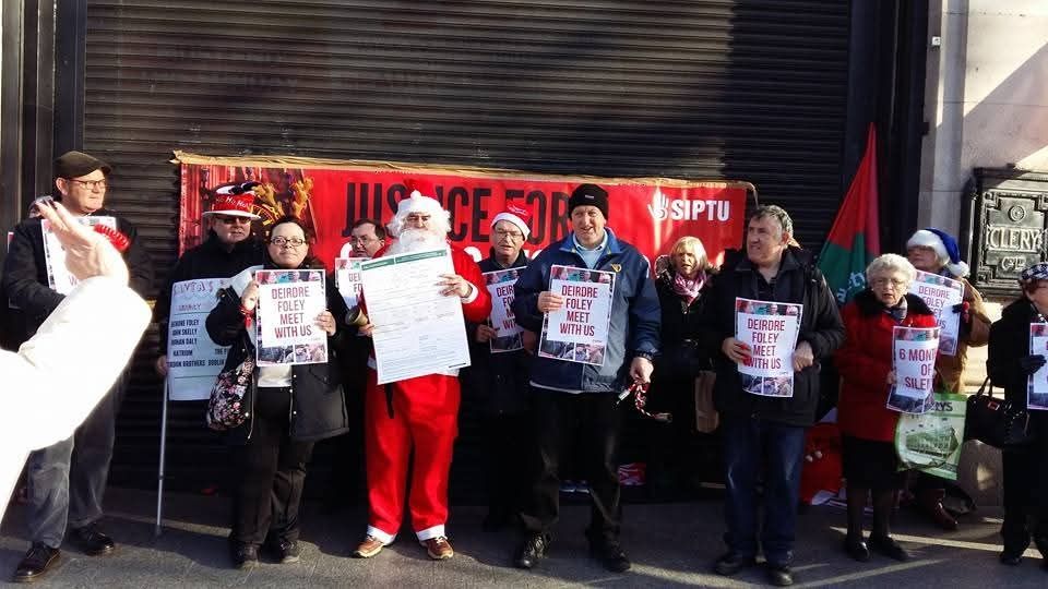 A picture of former Clerys workers outside the shop on Decemebr 8th 2015. Santa holds a large P45 while others have posters calling for a meeting with the new owners. They stand in front of a banner calling for justice for Clerys workers 