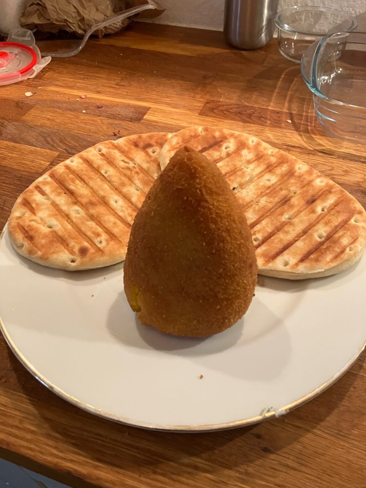 zwei panini hinter einem arancino auf teller 