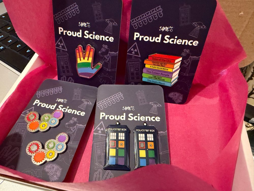 6 rainbow enamel pins gears, police boxes, stack of books and a LLAP hand. 