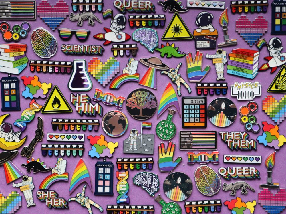A mixture of rainbow science pins eg dna, gears and astronauts 