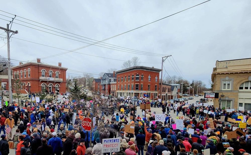 An intersection absolutely flooded with hundreds of protestors in every direction under a cold looking gray sky