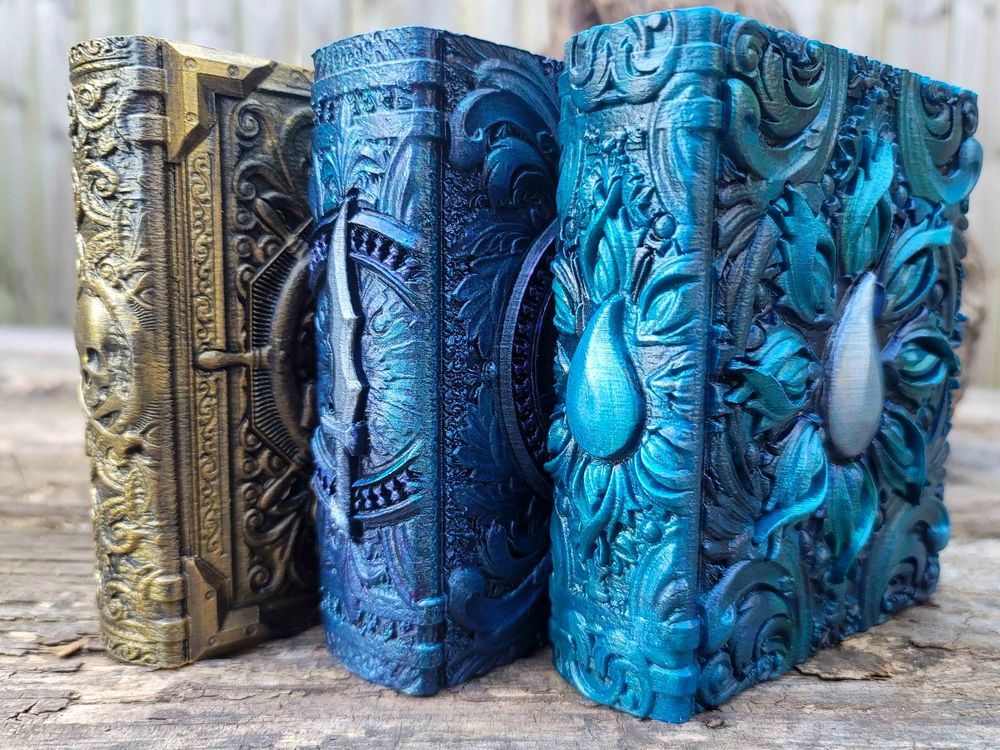 All three books from the side, showing that the spine has decorations and the pirate skull, knife, and water droplet.