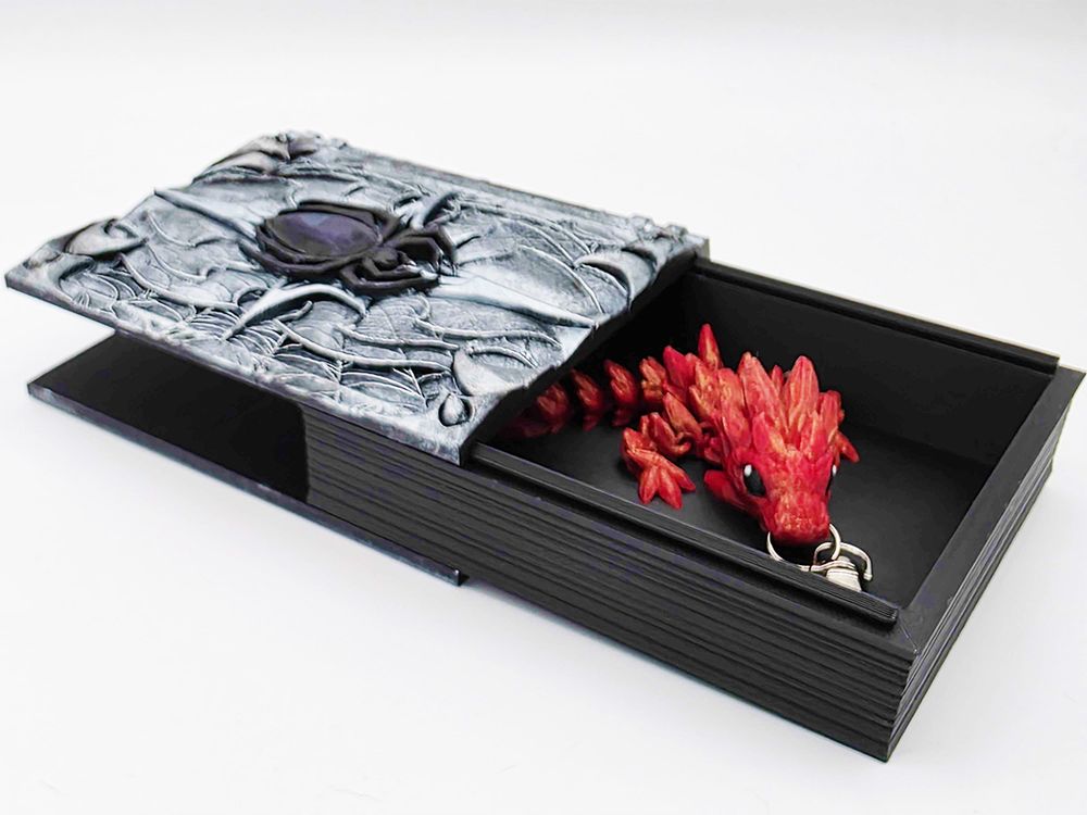 A shot of the book with the pages pushed up to reveal the box inside. Also I put a red dragon brushed with gold inside the box, as one does. It's also a keychain!