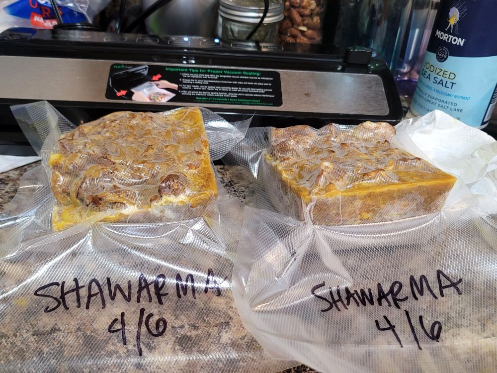 my cheap vacuum sealer with two 2 cup blocks of chicken shawarma that have been frozen and vacuum sealed and labeled April 6th