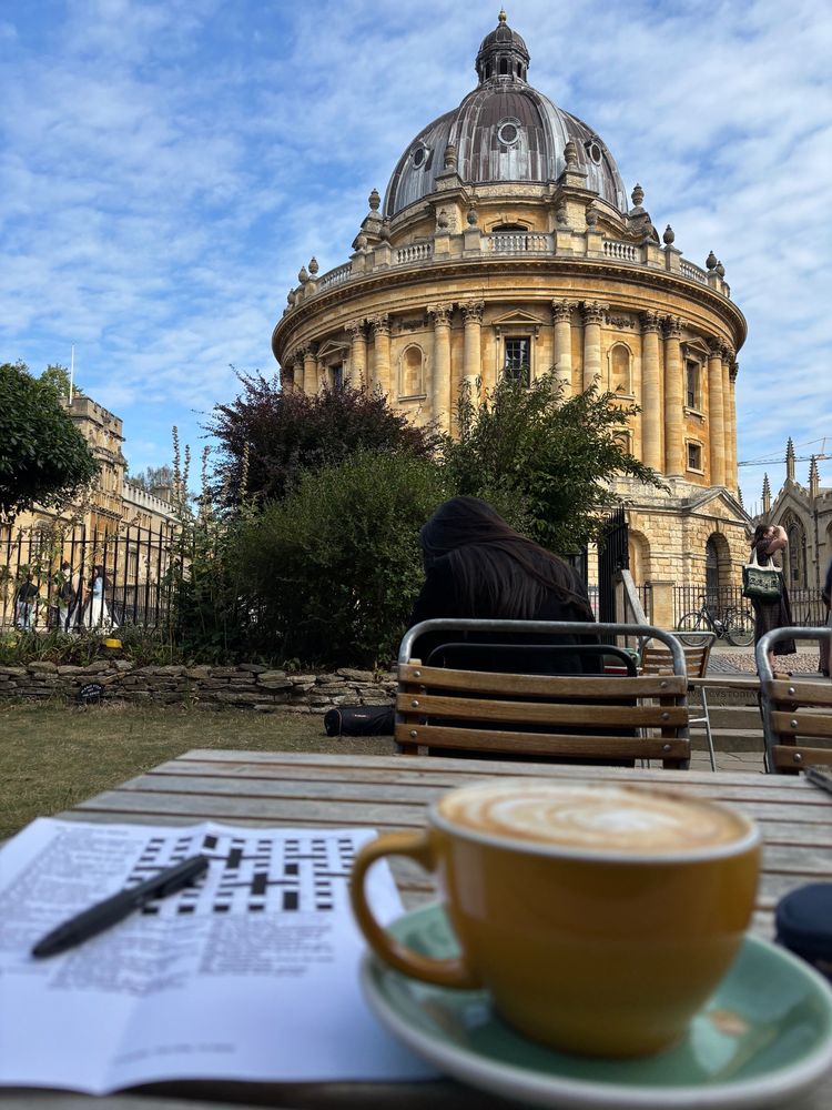 A cup of coffee and a crossword in front of the Radcliffe Camera in Oxford