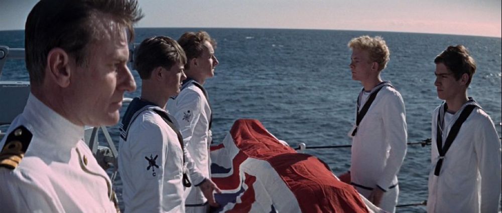 Sailors around a flag-draped body about to do a burial at sea