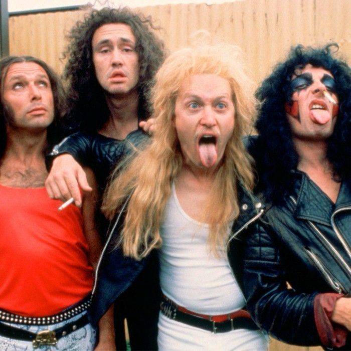 Four long haired men posing, two with tongues out 