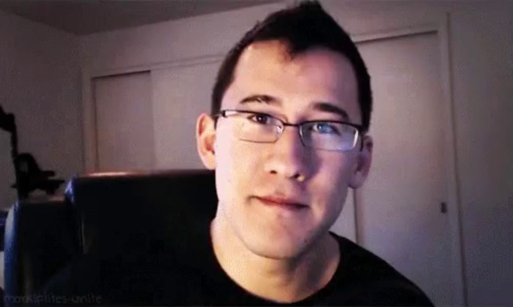 a man wearing glasses and a black shirt is sitting in a chair .