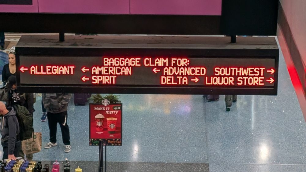 A marquee at Harry Reid (LAS) airport indicating baggage claims for Allegiant, American, Spirit, Advanced, Delta, Southwest, and Liquor Store. 