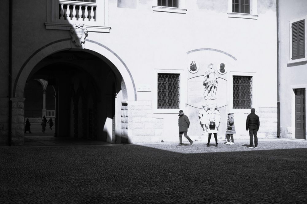 Cortile del Tribunale, quattro persone mentre guardano un’iscrizione.