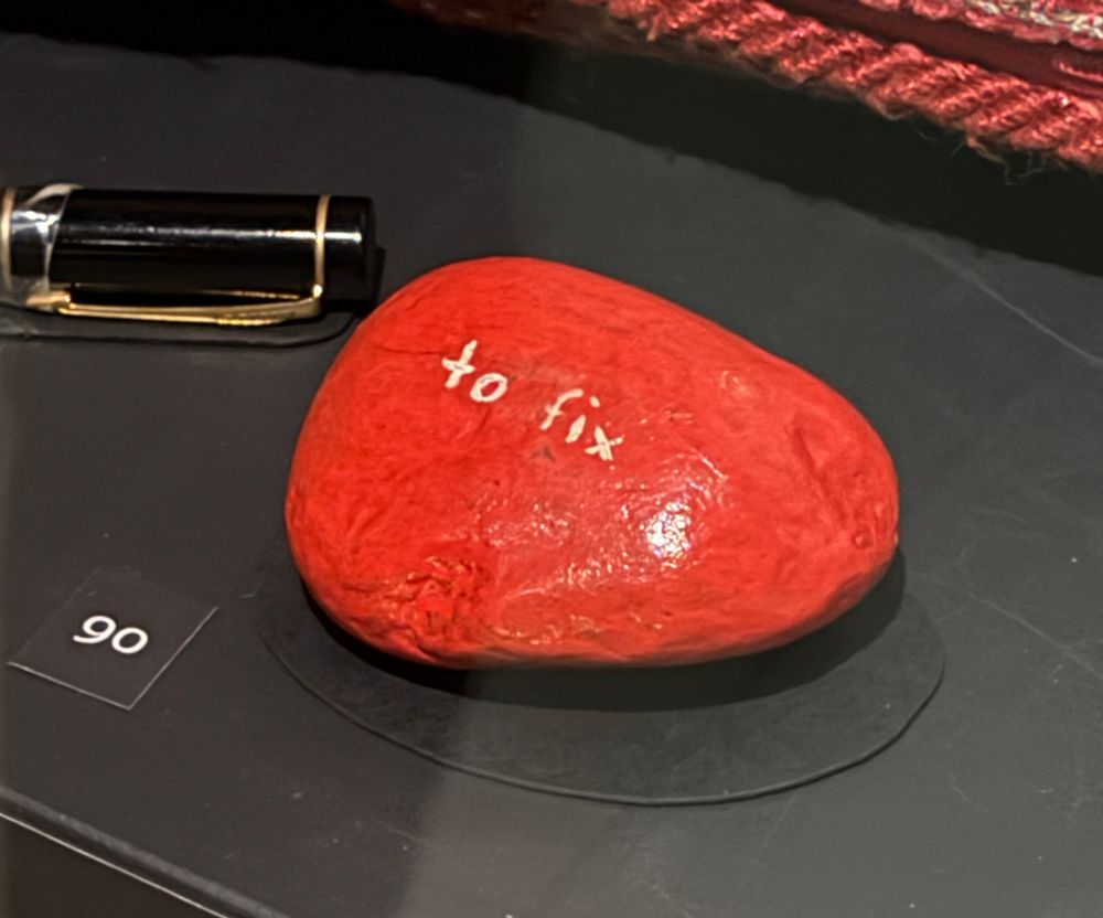 A red-painted pebble with “to fix” scratched onto it, visible in white