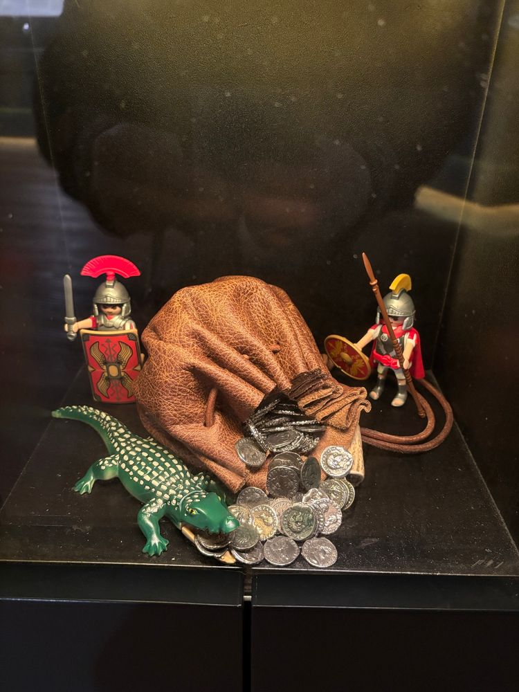 Playmobil Roman soldiers & crocodile in a museum display with coins.