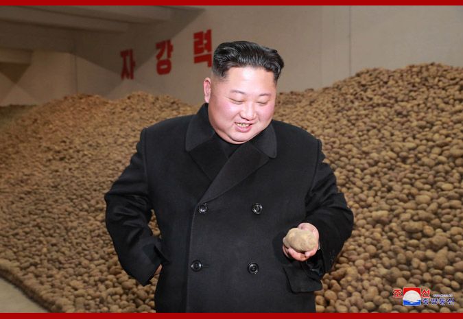 Kim Jong Un looks lovingly at a potato in a warehouse piled almost to the ceiling with potatoes. 