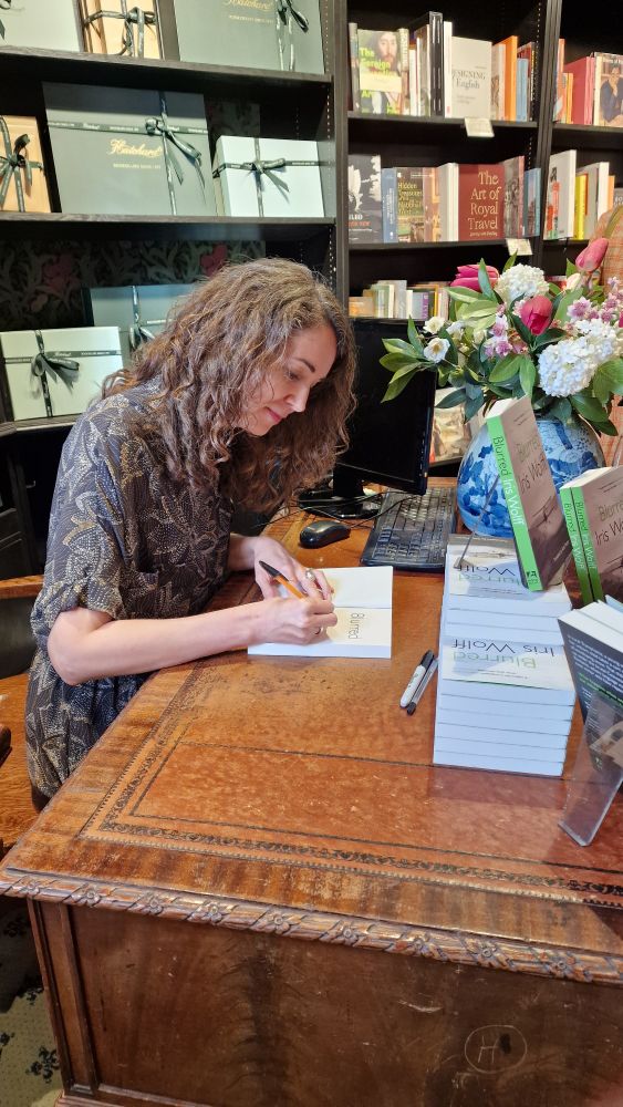 Iris signing a reader's copy at an antique desk