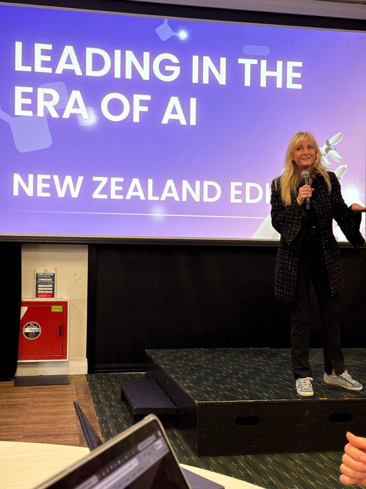 Holly Clark on stage in front of her presentation Leading in the era of AI