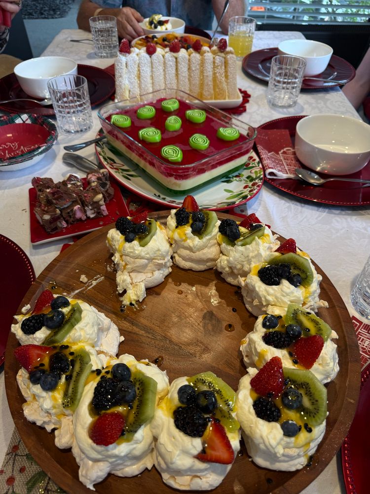 Pavlova merengues in a ring with strawberries blueberries blackberries and kiwifruit
