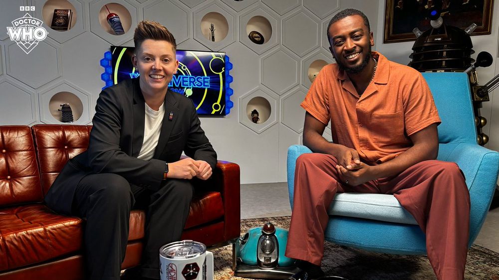 Christel Dee and Tyrell Charles on the set of the Whoniverse Show. Surrounding them several Doctor Who props can be seen, including a full-sized Dalek and Scoot the Polish-Bot.