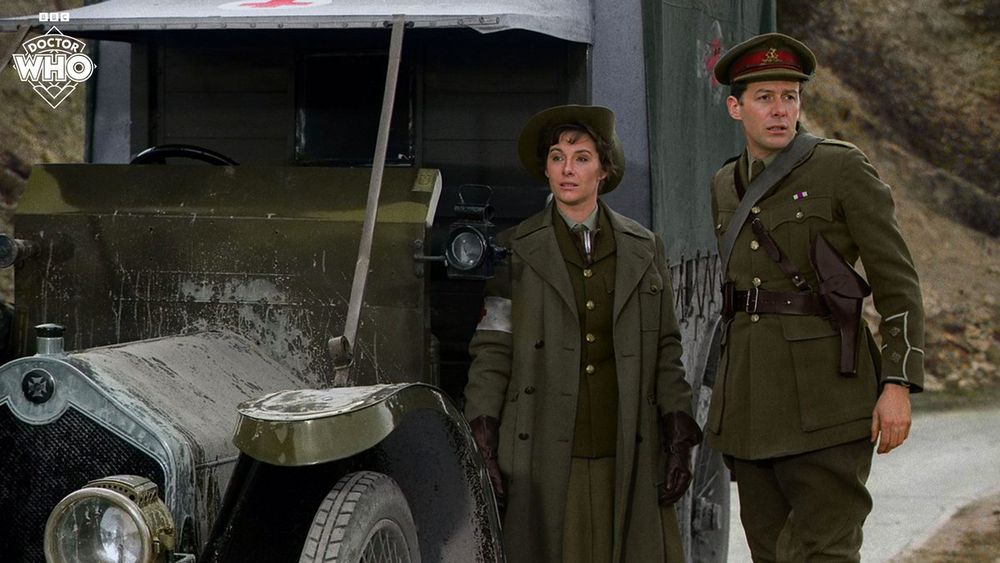 Two British officers, one man and one woman, standing next to a truck.
