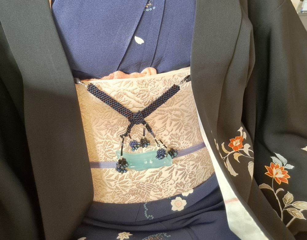 瑠璃紺地小紋着物に白っぽい袋帯、黒絵羽羽織。