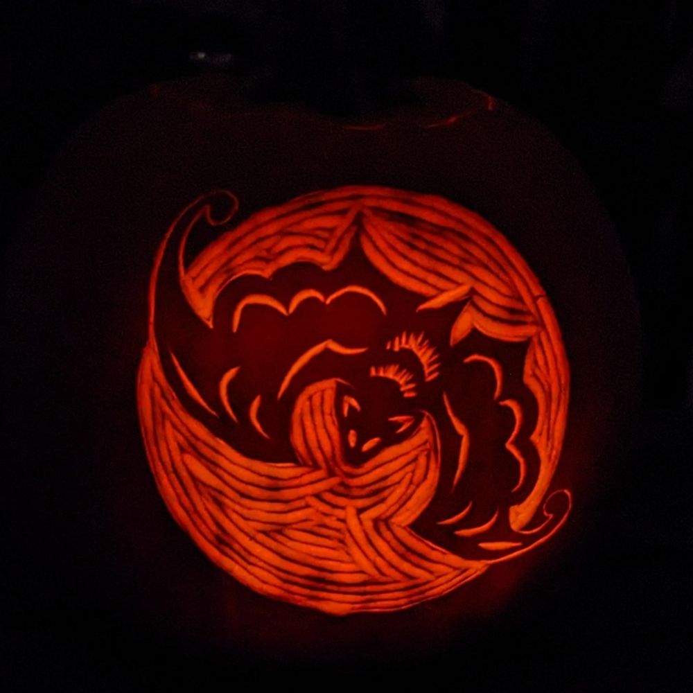 Jack o lantern with a bat carved into it at night time