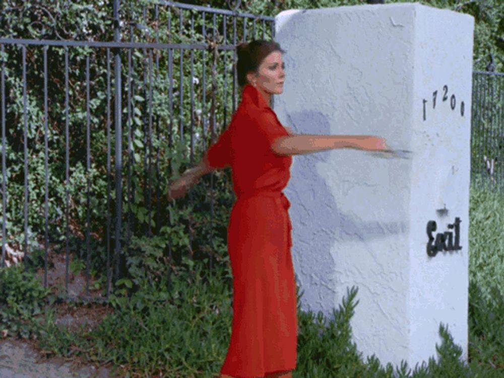 a woman in a red dress is standing in front of a white pillar with the word exit written on it