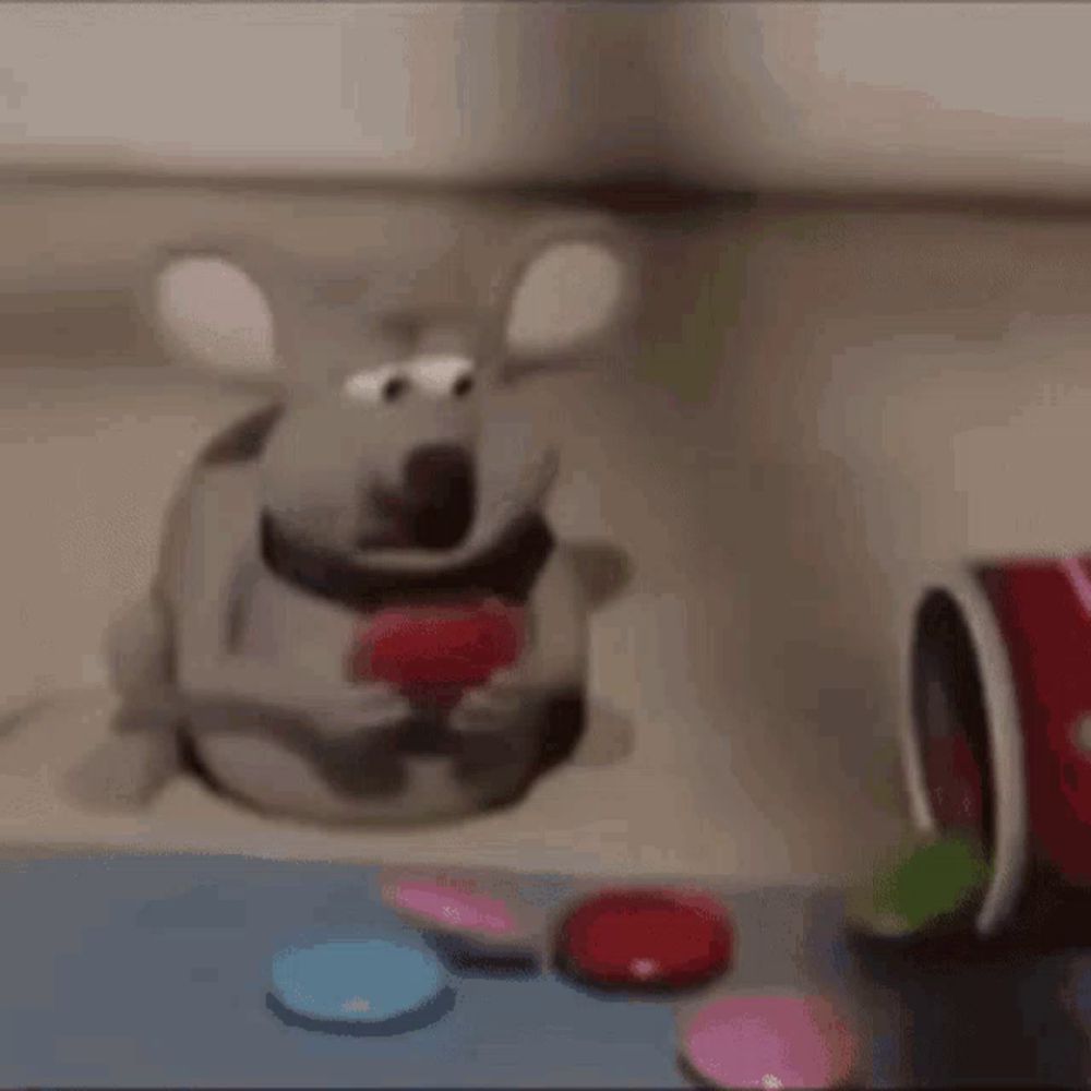 a stuffed mouse is eating a red heart next to a bucket of candy .