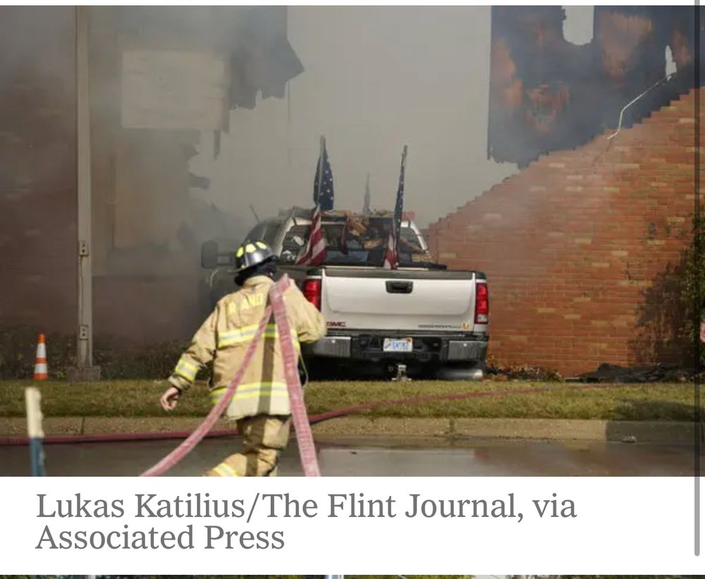 Fireman in the foreground walking towards a pickup truck that has been driven into a wall of a church. 
