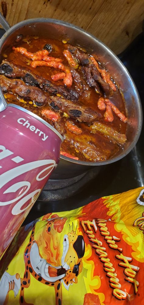 essential ingredients shown for secret recepie ribs .. ribs in a pot with flamin hot cheetos and cherry coke