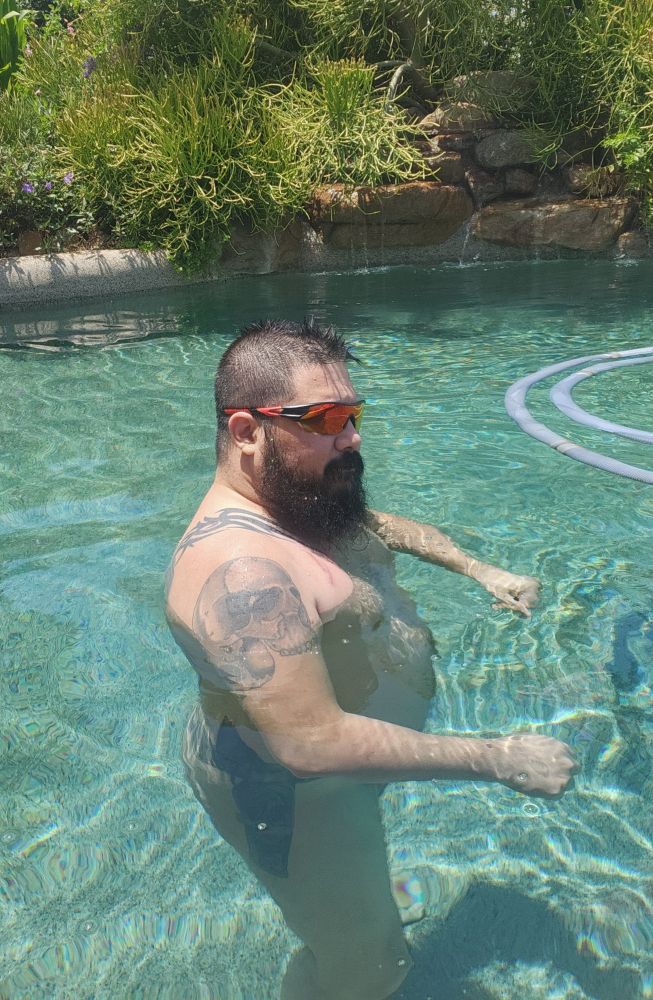 Naked tattooed bear swimming