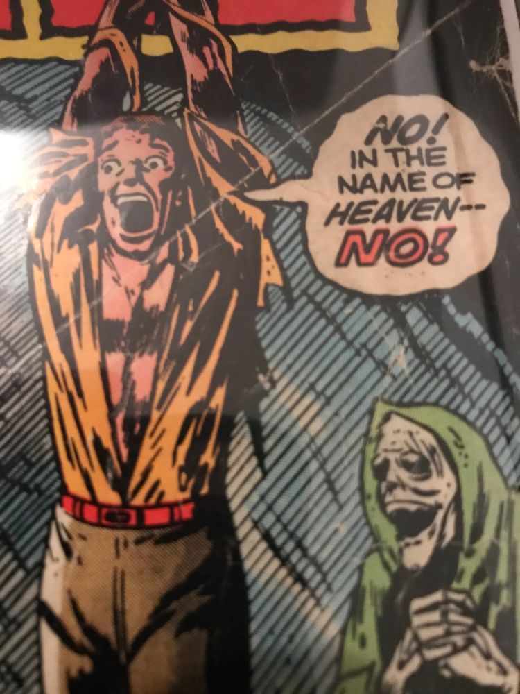 A detail from the cover of my personal copy of Uncanny Tales From The Grave #4. A man in a ripped shirt dangles from a rope in a cave full of skeletons, vampires and skeleton vampires.Including this li’l fella in the right hand corner in the green hood clasping his skeletal hands together. Tied-Up Man: “NO! In The Name Of Heaven— No!”